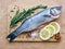 Raw uncooked sea fish preparation - seabass choice of fish on cutting board on the parchment paper. Mediterranean