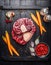 Raw veal shank slices meat and ingredients for Osso Buco cooking on black wooden background