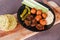 Raw veggies falafels and hummus on cutting board with corn bread