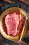 Raw Wagyu striploin, New york steak on a plate with pink peppper. Wooden background. Top view