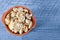 Raw washed mushrooms in ceramic pot on a blue background.