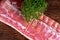 Raw whole back bacon loin with herb on wooden board