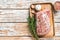 Raw Whole boneless pork loin meat with thyme and salt on rustic board. White wooden background. Top view. Copy space