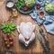 Raw whole chicken with vegetables and ingredients on wooden kitchen table for tasty cooking