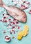 Raw whole fish on light turquoise background with ice cubes and ingredients, top view. Seafood concept.