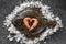 Raw whole flounder fish with shrimps stacked as a heart on ice over dark stone background. Creative layout made of fish, top view