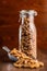 Raw whole grain fusilli pasta. Uncooked pasta in scoop on wooden table