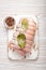 Raw wrapped rolled sliced pork with bay leaf and seasonings on white cutting board on rustic white wooden background top