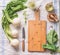 Raw young turnip with greens on light kitchen table with empty cutting board and knife, top view. Healthy vegetarian clean eating