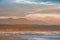 Rays of golden evening light falling on the Plettenberg Bay beach at sunset, with mountains in the distance.