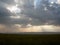 Rays of light streaming through dark clouds over African plains