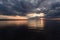 Rays of the sun in a moody rainy cloudy sky with a reflection on the surface of the water