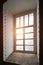 Rays of the sun at sunset make their way through a large old window in a tower with thick stone walls