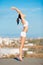 Reach for the sky. an attractive young woman in workout gear stretching on a rooftop.