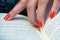 Reading a book with orange finger nails