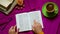 Reading Holy Bible and follow with finger on purple background from above