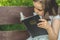 Reading the Holy Bible in outdoors. Christian girl holds bible in her hands sitting on a bench