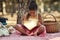 Reading is one way to nurture a childs curiosity. a little girl reading a book with glowing pages in the woods.