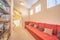 Reading room interior with long red couch in front of wall shelves with books