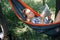 Reading woman lying in a hammock, in a shadow, between two big trees.