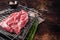 Ready for cooking on grill Boneless lamb meat, raw neck meat with herbs. Dark background. Top view. Copy space