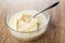 Ready flour mixture with butter, milk for muffins, spoon in bowl on wooden table