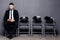 Ready for interview. Handsome man in formalwear holding phone and use it while sitting at the chair in waiting room