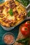 Ready Italian lasagna, on a green wooden background with basil, tomatoes. Culinary background, book of Italian recipes, delicious