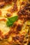 Ready Italian lasagna, on a green wooden background with basil, tomatoes. Culinary background, Italian recipe book, delicious food