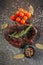 Ready meat steak on a dark metal cutting board, next to a sprig of aromatic rosemary, tomatoes, a black mug with mixed peppercorns