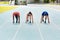 Ready for a race. Full length shot of three young athletes in the set position out on the running track.