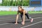 Ready to go. Close up photo of female athlete on low start starting line. Girl on Stadium track, preparing for a run. Sports and