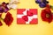 Real box with white and red bow and ribbon with different flowers top view on Valentine`s day isolated on yellow background. Flat