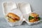 real burgers in a plastic container on the table, food delivery concept,selective focus