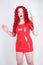 Real doll woman wearing red latex rubber dress and posing on white studio background alone. curvy plus size adult girl standing as