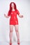 Real doll woman wearing red latex rubber dress and posing on white studio background alone. curvy plus size adult girl standing as