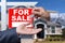 Real Estate Agent Handing Over the House Keys in Front of a Beautiful New Home and For Sale Real Estate Sign.