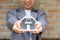 Real estate agent hands holding the home model stand in front of the red brick wall background or Sales presenting home insurance