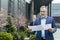 Real estate agent. Handsome senior serious man in suit and beard standing on street near houses