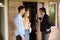 Real estate agent inviting young married couple to enter house for sale
