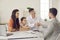 Real estate agent shaking hands with happy father sitting with wife and daughter after successful deal