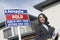 Real Estate Agent By Sold Sign Outside House