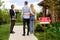 Real estate broker showing house for sale to young couple, outside