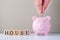 Real estate business investment and finance accounting concept. Hand putting coin into pink piggy bank.