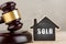 Real estate concept auction gavel and little house with inscription Sold