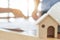 Real estate concept, image of toy wooden house over blurred engineer working background