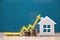 Real estate market, graph, up arrow. House model and a stack of coins. The concept of inflation, economic growth, the