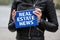 REAL ESTATE NEWS. Woman holding blue notebook with text