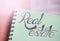 Real estate words lettering on spiral copybook page put on pink background. Selective focus. Real estate investment rental