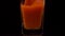 The real juice. Super slow motion shot of pouring tomato juice into a transparent glass against black background. Close